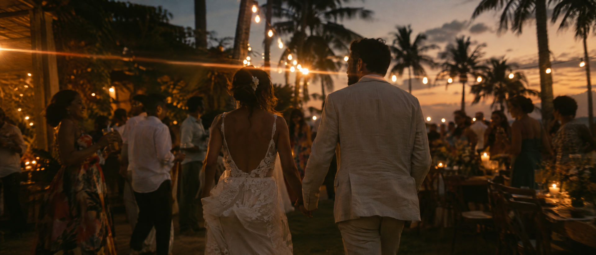 Casal de mãos dadas na festa ao entardecer depois da correção de cor, com pele natural, luzes âmbar e céu profundo