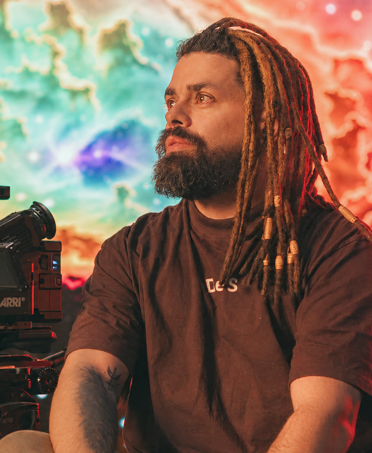 Jamerson sentado ao lado de uma câmera de cinema, diante de um painel de luz colorido